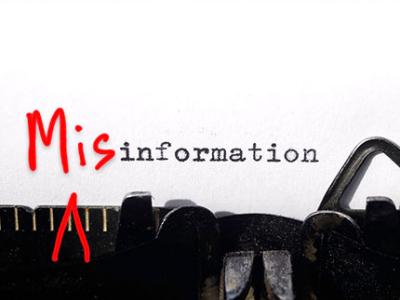 "Mis" is scrawled in bright red in front of the word "information" on a white piece of paper in an old-fashioned typewriter to make the word misinformation.