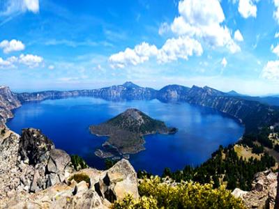 Panoramic view of mountain range with a huge crater lake and land mass emerging from the center of the lake.